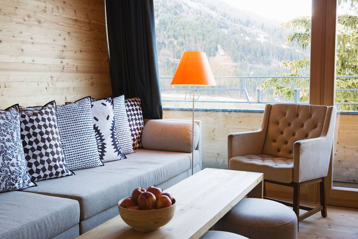 Una sala de estar moderna con un sofá, una silla, una mesa y una lámpara.