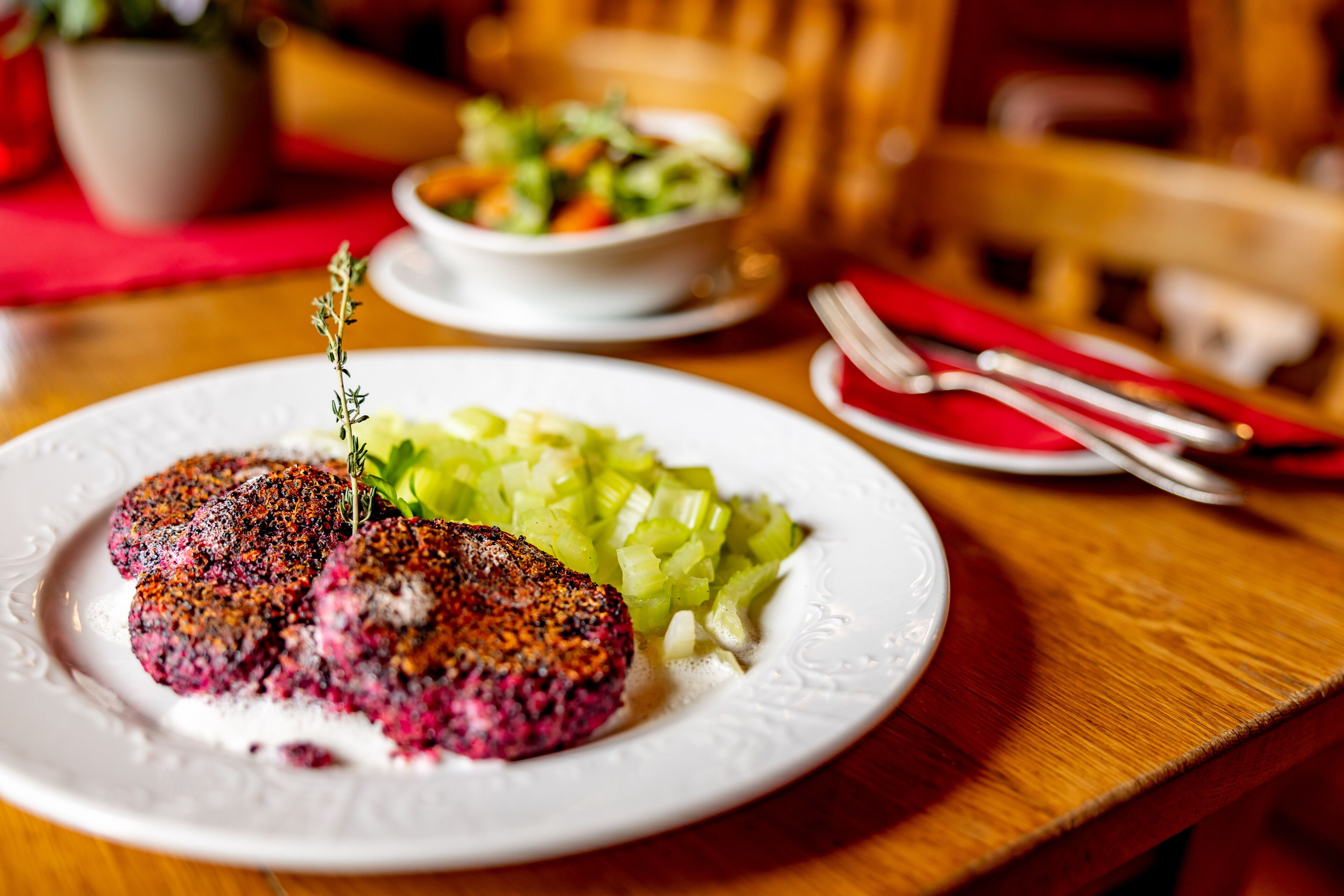 A plate with a meat dish and a side of pickled vegetables on a wooden table.