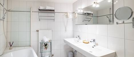 A modern bathroom with a large white sink, a glass shower enclosure, and a mirror with lights.