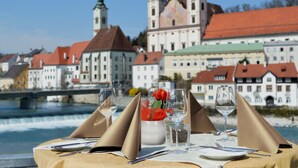 A table set for dining with a view of historic buildings and a river.
