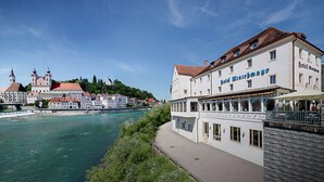 A riverside hotel with a view of a historic building across the river.