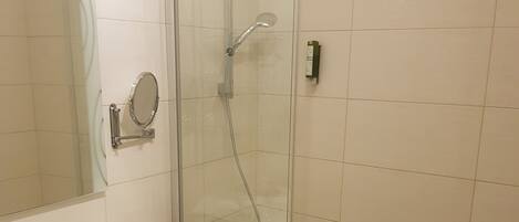 A modern bathroom with a glass-enclosed shower, a white sink, and a large mirror.