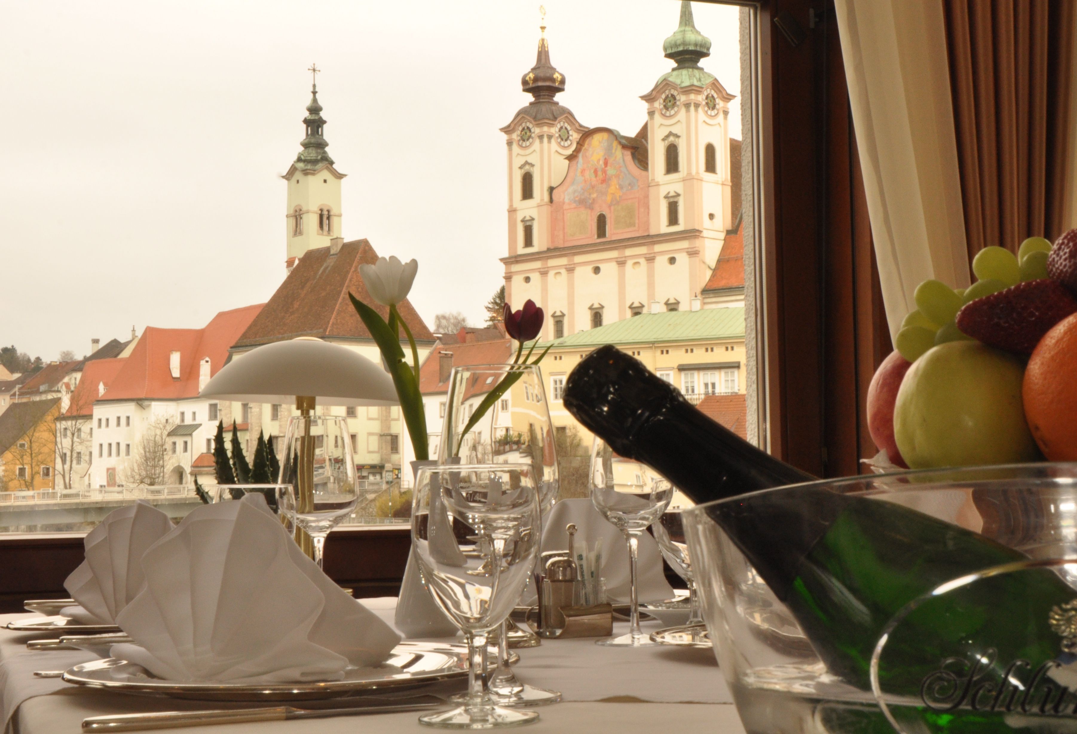 Une table dressée pour le dîner, avec vue sur un bâtiment historique doté de nombreuses flèches.