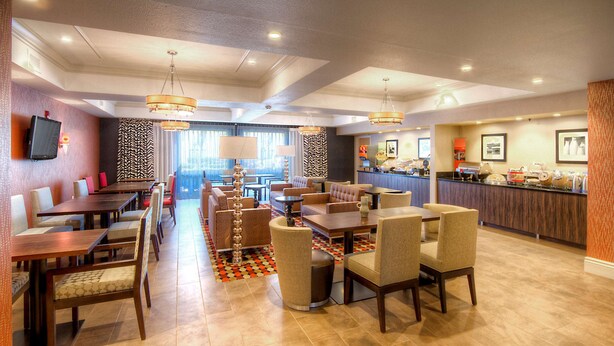 A hotel lobby with multiple seating areas, a reception desk, and a buffet. - Hampton Inn Fremont (Fremont)