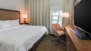 A hotel room with a large bed, two bedside lamps, a flat-screen TV, a desk with a chair, and a large window with curtains. - Hampton Inn Memphis-Southwind (Memphis)