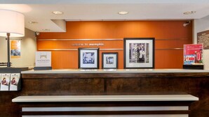 A reception desk with a 'Welcome to Memphis' sign, framed photographs, and a Coca-Cola advertisement. - Hampton Inn Memphis-Southwind (Memphis)