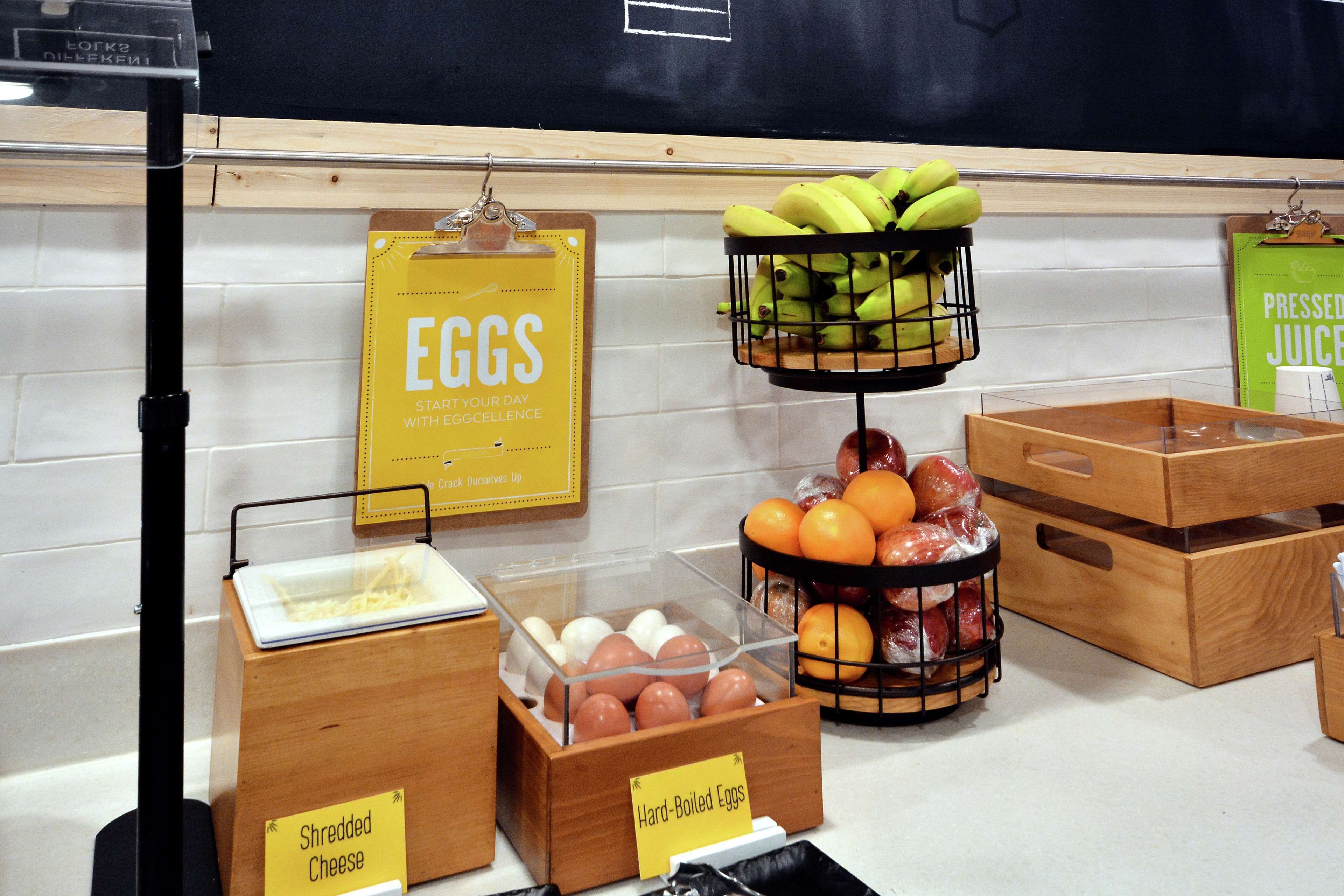 Un assortiment de produits pour le petit-déjeuner comprenant des œufs durs, du fromage râpé, des bananes, des oranges et du jus de fruits frais.