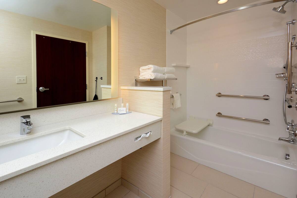 A modern bathroom with a white sink, mirror, and bathtub.