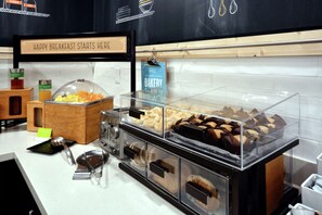 A breakfast buffet with various food items and a sign that reads "HAPPY BREAKFAST STARTS HERE".