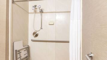A shower area with a handheld showerhead, a wall-mounted faucet, and a towel rack.