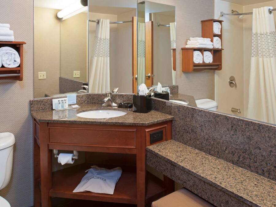 Un baño con lavamanos de granito, un espejo, toallero y cortina de ducha.