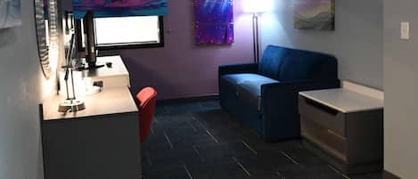 Een moderne kamer met een bureau, computer en zithoek.