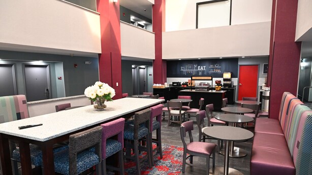 Un vestíbulo de hotel con zona de bar, asientos y un centro de mesa floral.