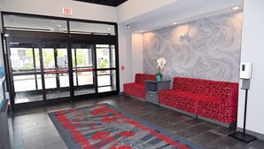 Un vestíbulo de hotel con un sofá estampado en rojo, una pared de mármol y una alfombra con motivos rojos y azules.