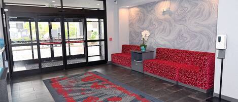 A hotel lobby with a red patterned sofa, a marble wall, and a red and blue patterned carpet.