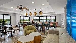 Un moderno vestíbulo de hotel con comedor, asientos y vistas al exterior.