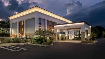 A modern hotel with a covered entrance, a parking lot, and a well-maintained landscape.