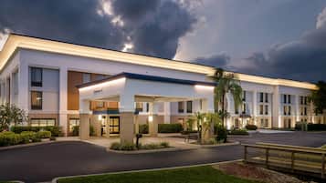 A modern hotel with a covered entrance, a parking lot, and well-maintained landscaping.