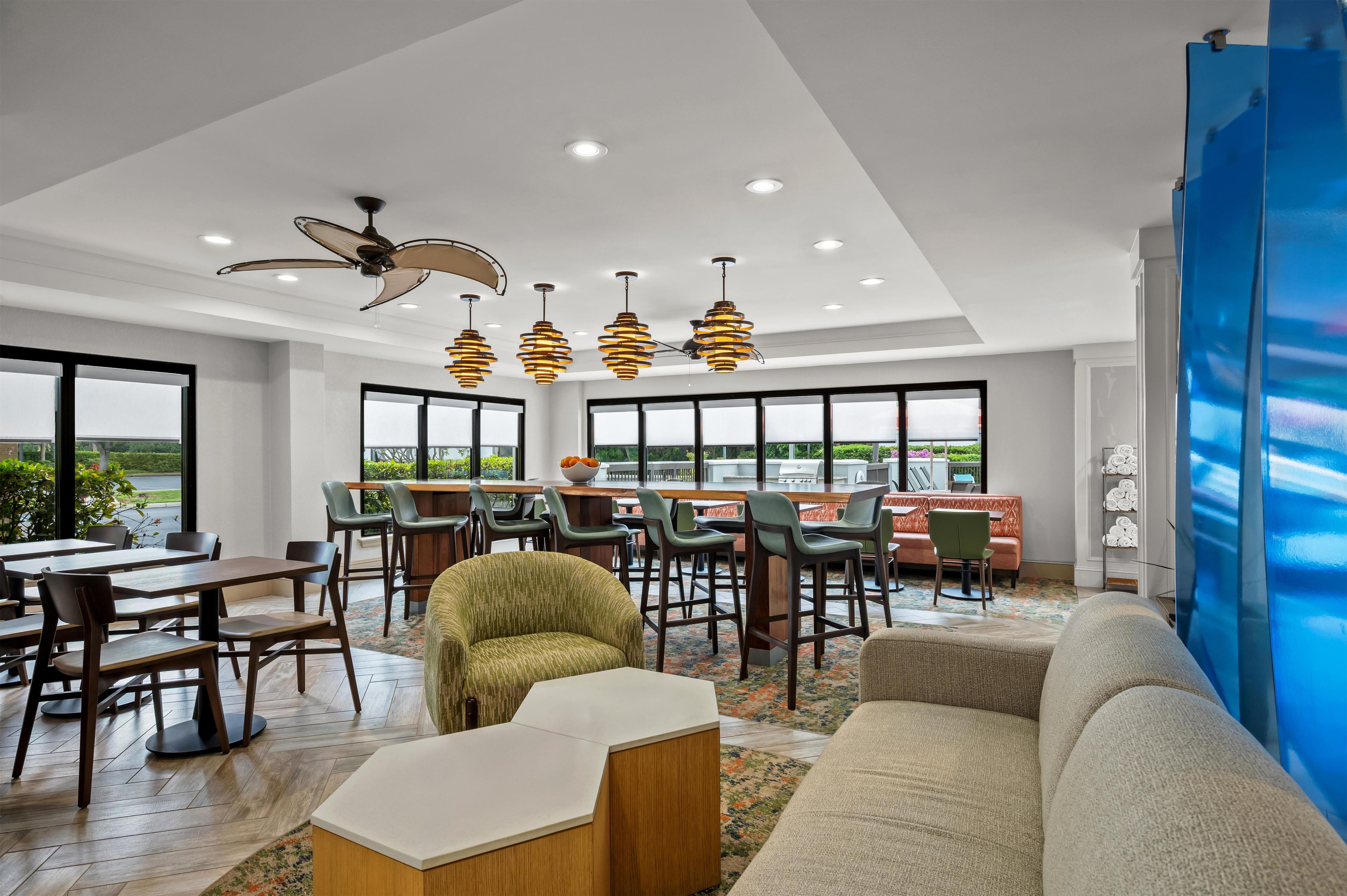 A modern hotel lobby with a dining area, seating, and a view of the outdoors.