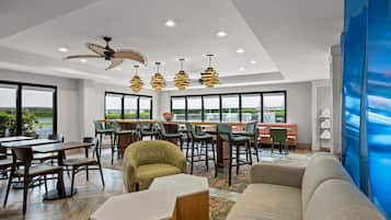 A modern hotel lobby with a dining area, seating, and a view of the outdoors.