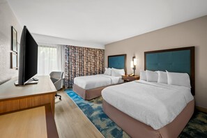 A hotel room with two beds, a desk, a TV, and a patterned curtain. - Hampton Inn - Naples - I-75 (Naples)