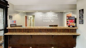 A hotel reception desk with a 'Welcome to the Palmetto State' sign, a 'Manager On Duty' sign, and a 'Hilton Honors' sign. - Hampton Inn Gaffney (Gaffney)