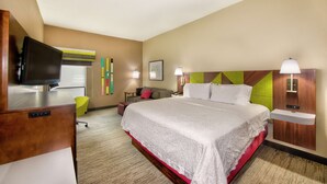 A hotel room with a large bed, a desk with a television, a chair, and a small table. - Hampton Inn Gaffney (Gaffney)