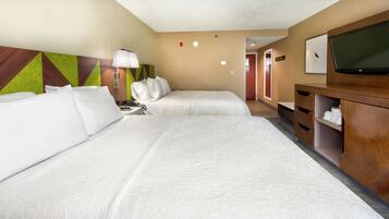 Une chambre d’hôtel avec deux lits, un bureau, une télévision et un miroir.