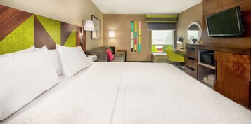 A hotel room with a large bed, a desk with a chair, a television, and a window with a view.