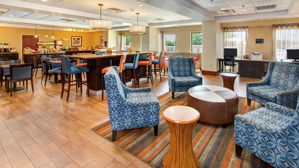 A hotel lobby with a bar area, seating with patterned upholstery, and a central coffee table. - Hampton Inn Gaffney (Gaffney)