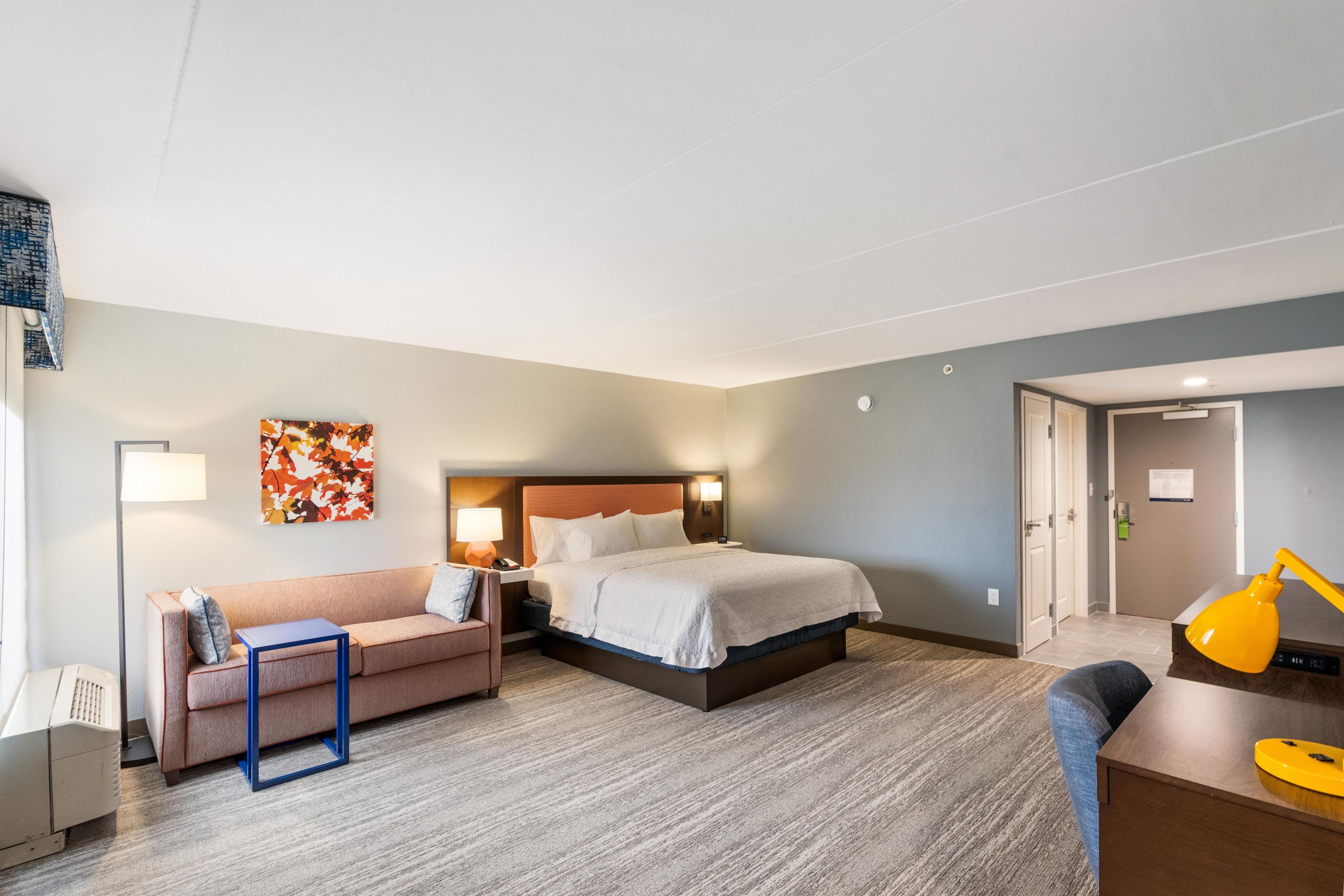 Une chambre d’hôtel avec un lit, un canapé, un bureau et une lampe.