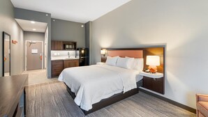 A hotel room with a large bed, a bedside table with a lamp, a small desk, and a kitchenette area. - Hampton Inn Winchester N/Conference Center, VA (Winchester)