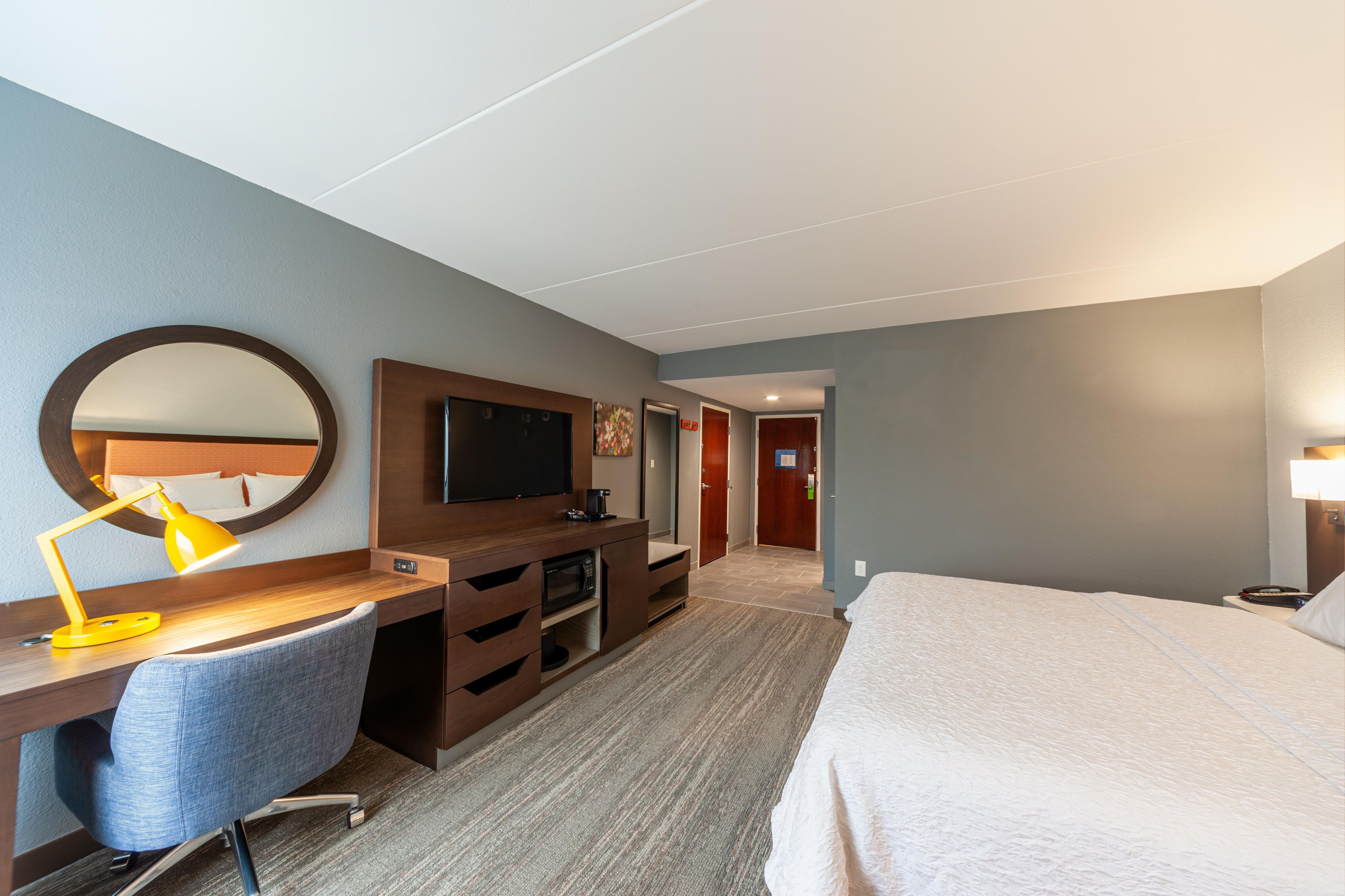 Une chambre d’hôtel comprenant un lit, un bureau avec une chaise, une télévision et un miroir.