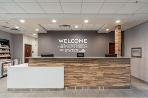 A reception desk with a 'WELCOME TO THE MOTHER OF STATES' sign, a 'Hilton Honors' badge, and a 'STAFF ONLY' door. - Hampton Inn Winchester N/Conference Center, VA (Winchester)