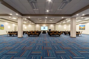 A conference room with a large screen, multiple tables, and chairs arranged for meetings. - Hampton Inn Winchester N/Conference Center, VA (Winchester)