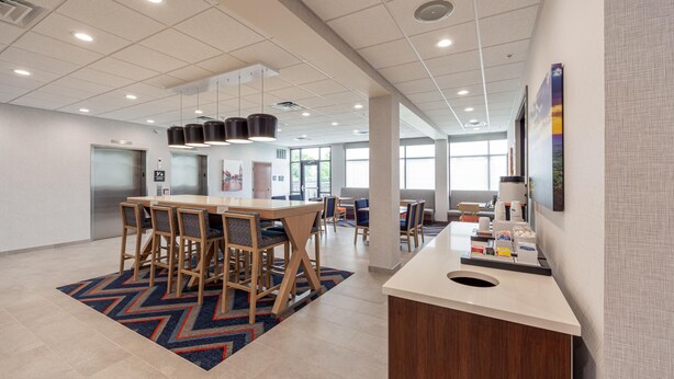 A modern hotel lobby with a reception desk, seating area, and a large window providing natural light. - Hampton Inn Winchester N/Conference Center, VA (Winchester)
