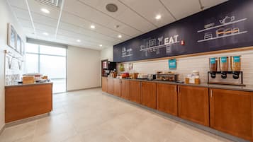 A clean, modern kitchen area with a long counter, wooden cabinets, and a black backsplash with kitchen-related illustrations.