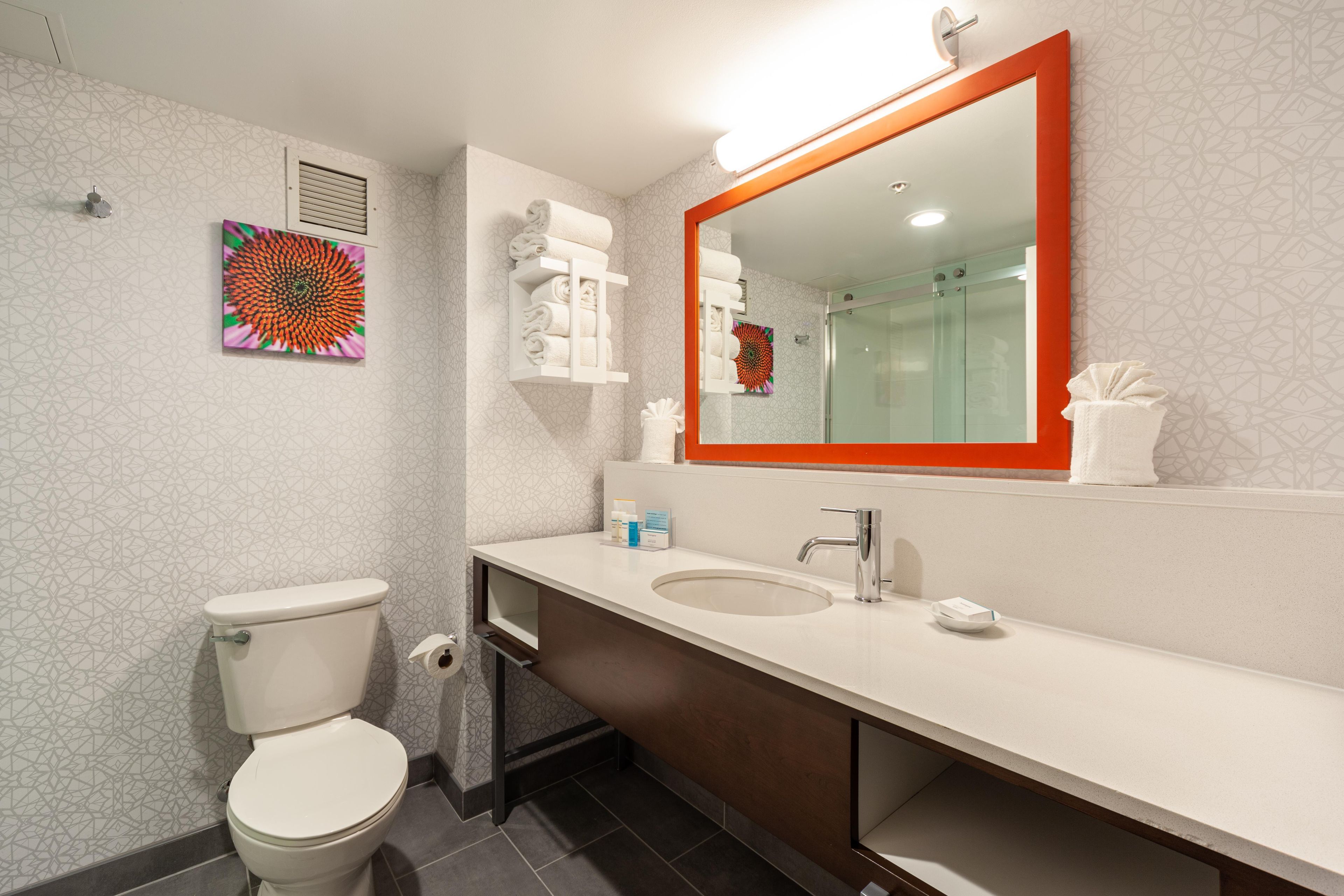 A modern bathroom with a toilet, sink, and shower.