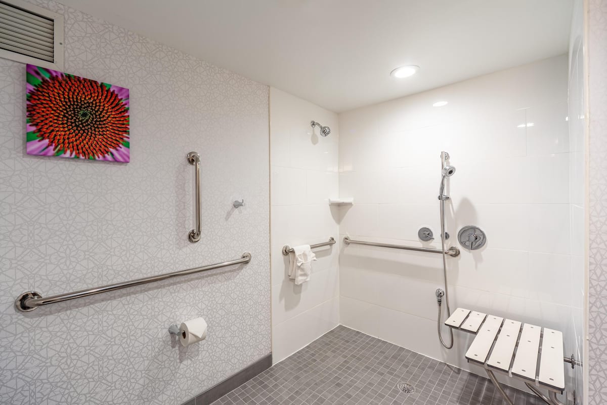 Une salle de bain équipée d’une douche, de barres d’appui, d’un sèche-mains et d’un porte-serviettes.