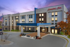 Un hotel Hampton Inn con fachada moderna, múltiples ventanas y una entrada acogedora.