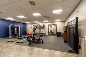 A gym with various exercise equipment, a mirror, and a door to another room. - Hampton Inn Winchester N/Conference Center, VA (Winchester)