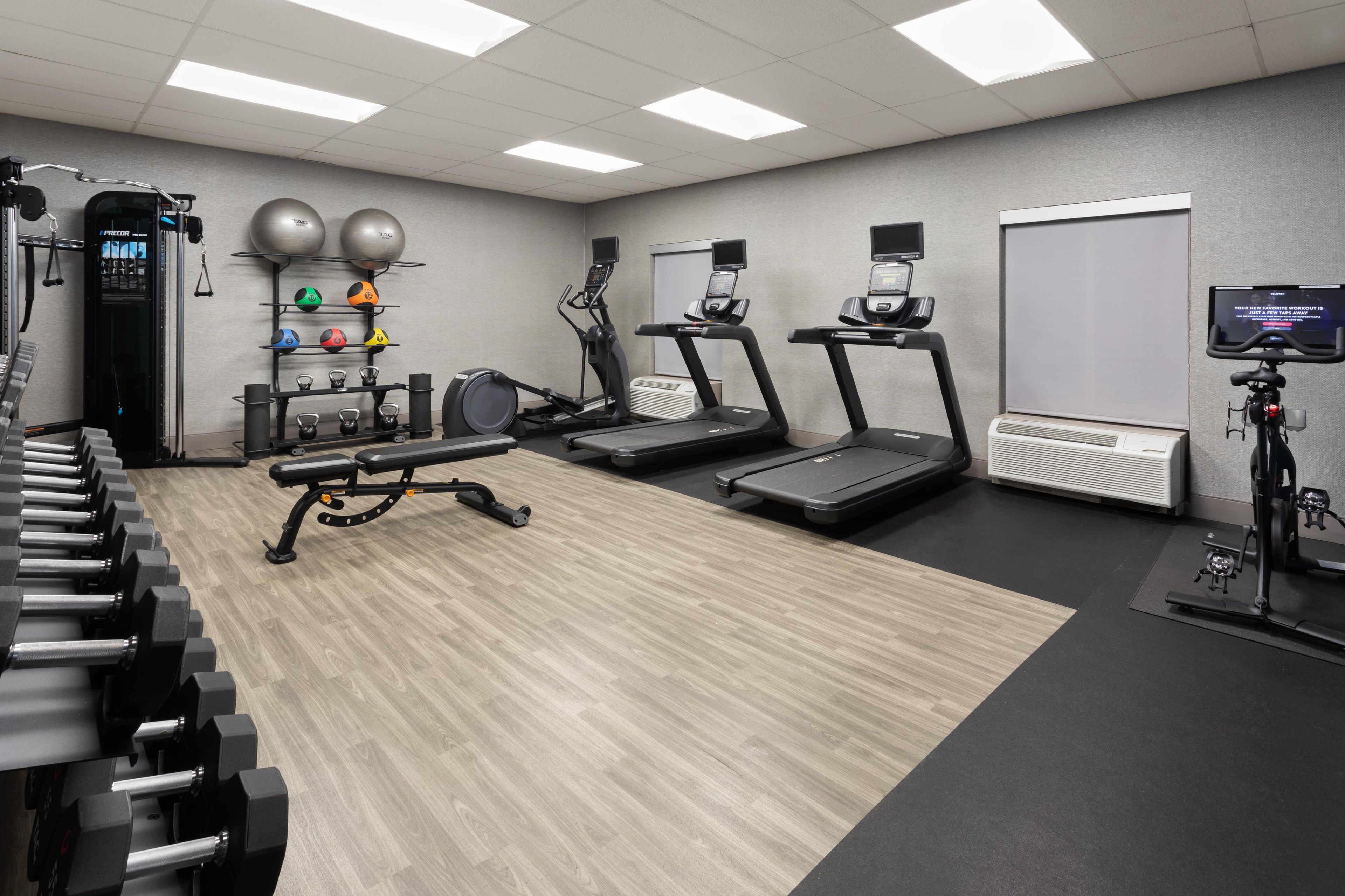 Un gimnasio con cintas de correr, una máquina de remo y pesas.