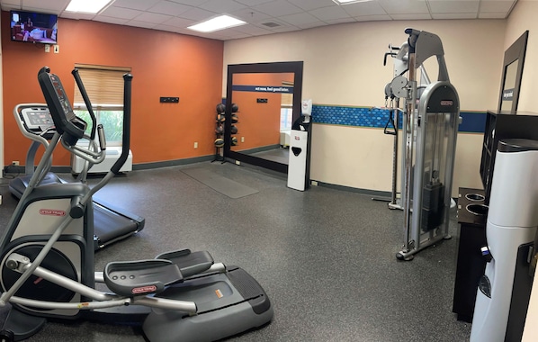 A gym with treadmills, an elliptical, a weight machine, and a water dispenser.
