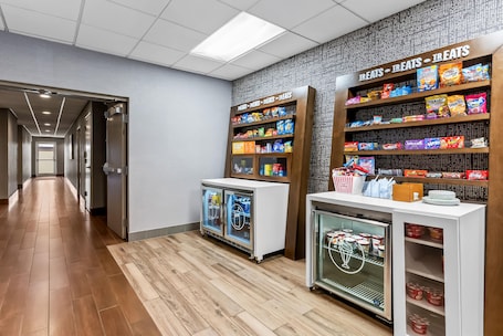 A hallway with a snack bar featuring various packaged snacks and a refrigerated display.