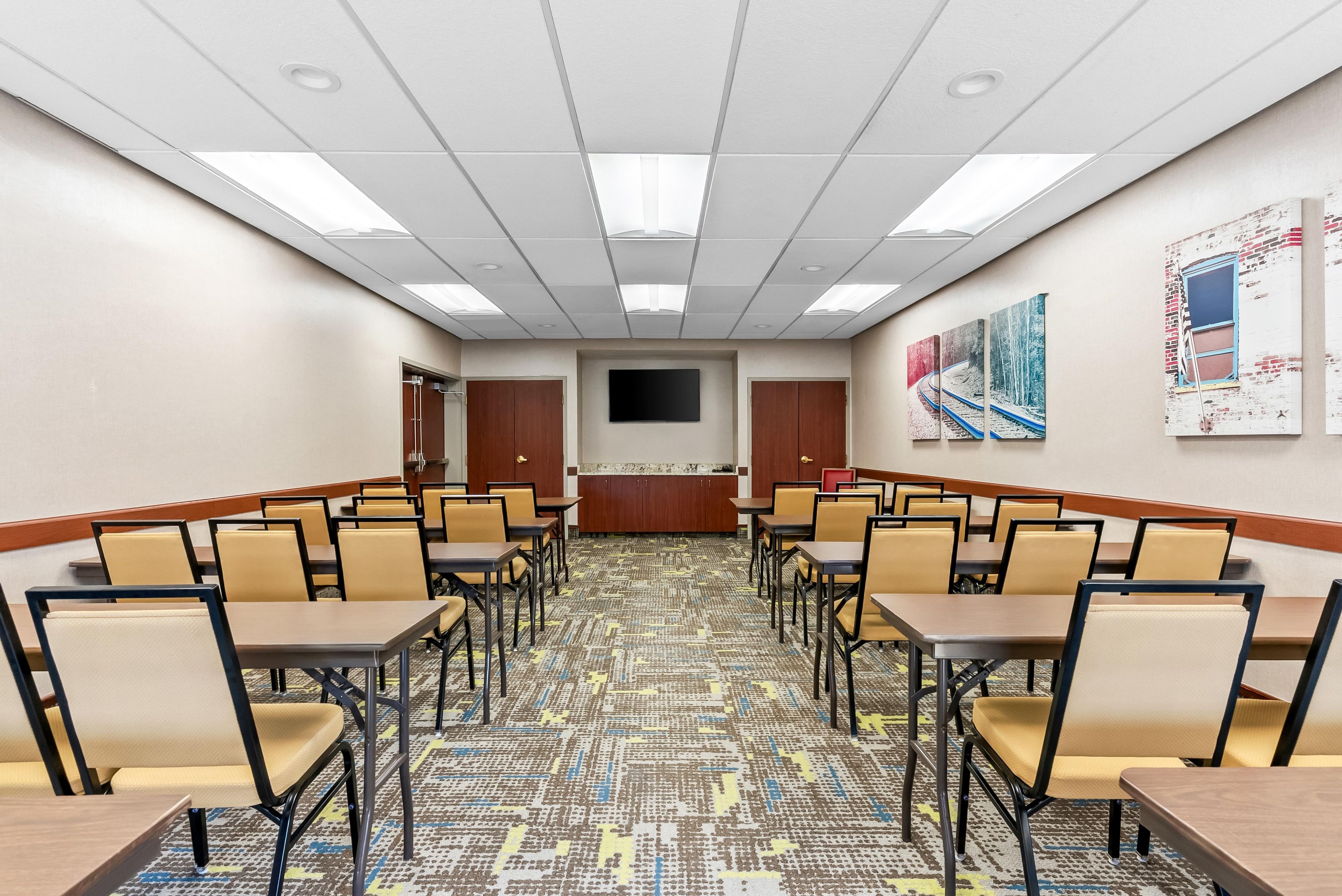 A conference room with a patterned carpet, beige chairs, and tables arranged for meetings.