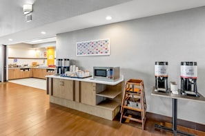 A modern kitchen area with a microwave, coffee machines, and a coffee station.
