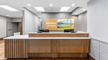 A reception desk with a 'Welcome to Hampton' sign, a wooden counter, and a painting above.