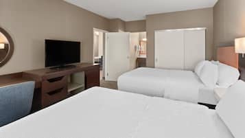 A hotel room with two beds, a TV, a desk, and a mirror.
