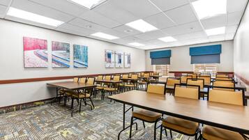 A conference room with tables and chairs, artwork on the walls, and a patterned carpet.