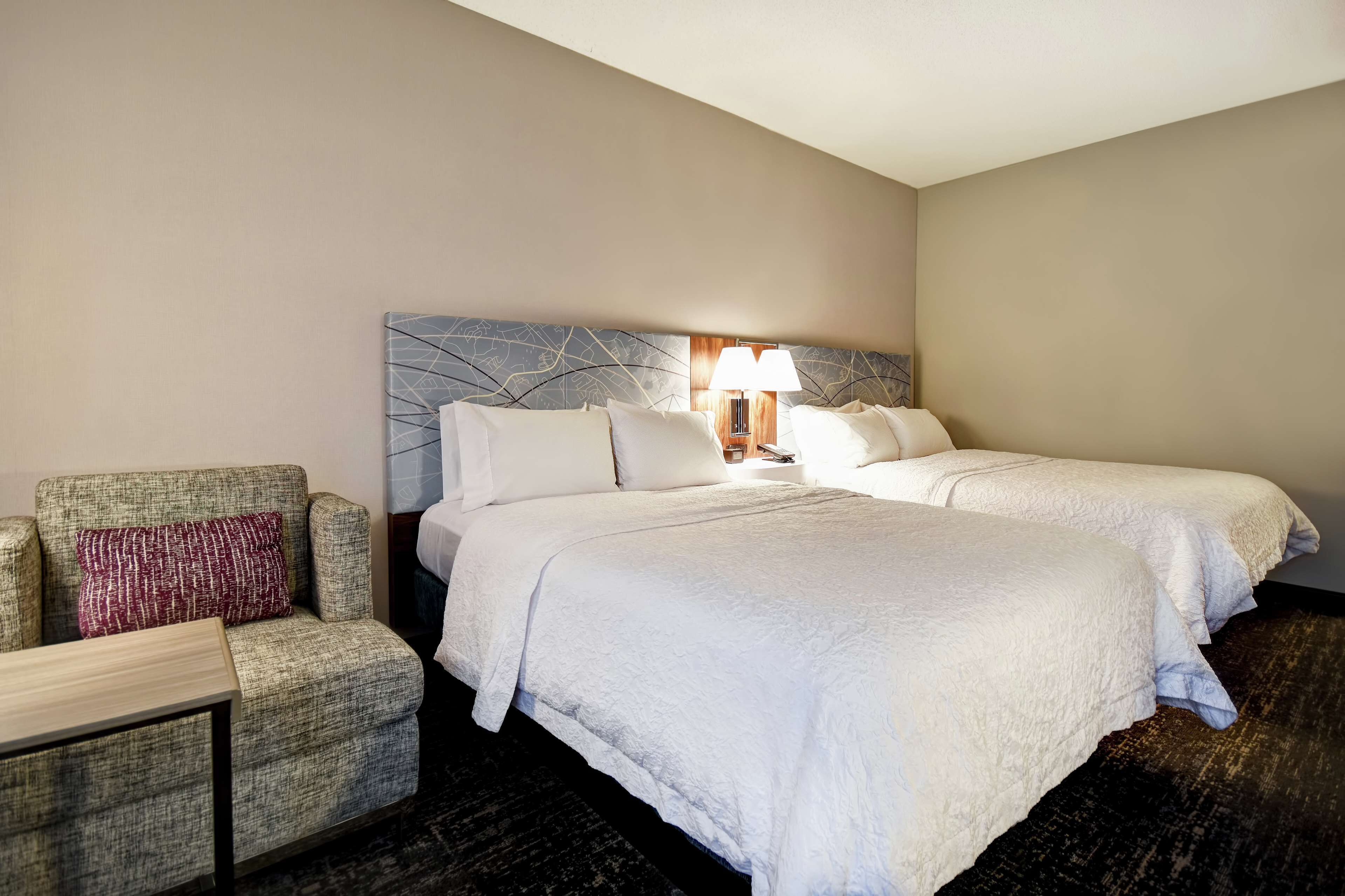 Een hotelkamer met twee bedden, een slaapbank en een lamp.